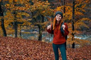 herfst park gedaald bladeren hoog bomen rivier- in de achtergrond en vrouw reizen toerisme foto