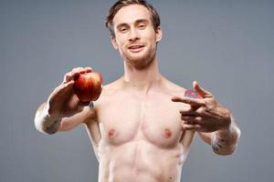 atletisch Mens met een opgewonden torso en een tatoeëren Aan zijn arm rood appel Gezondheid foto