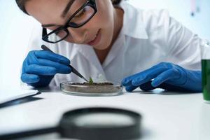 vrouw in wit jas onderzoekt planten microbiologie professioneel foto