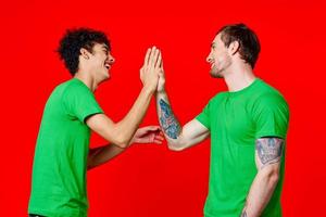 twee vrienden in groen t-shirts communicatie rood achtergrond studio foto