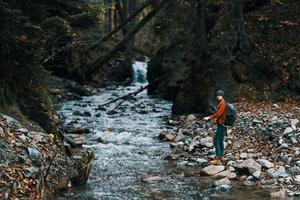 reiziger met rugzak landschap bergen transparant rivier- vijver en Woud in de achtergrond foto