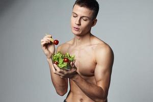 atletisch vent met een gemotiveerd omhoog lichaam gezond voedsel groente salade bijgesneden visie foto