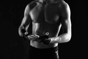 Mens met halters in zijn handen naakt gespierd lichaam training donker achtergrond foto