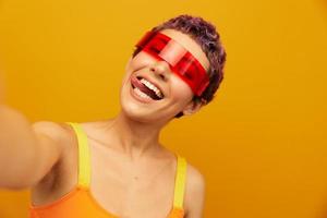 vrouw vervelend ongebruikelijk millennial bril nemen selfies in sportkleding tegen een oranje studio achtergrond, vrij ruimte foto