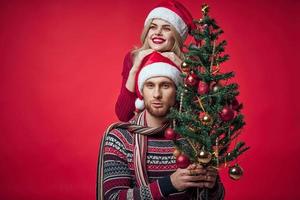 Mens en vrouw Kerstmis boom decoratie pret vakantie rood achtergrond foto