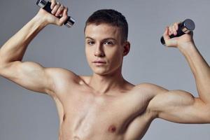 knap Mens met een opgewonden lichaam halters in zijn handen training spieren foto