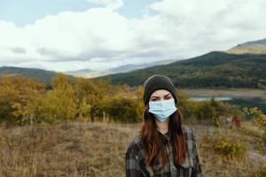 vrouw wandelaar in medisch masker gras natuur herfst bergen foto