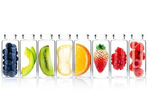 Zelfgemaakte huidverzorging met fruitingrediënten van avocado, sinaasappel, bosbes, granaatappel, aardbei en framboos in glazen flessen geïsoleerd op een witte achtergrond foto