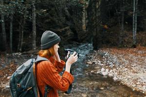 vrouw met een camera Aan natuur in de bergen in de buurt de rivier- en hoog bomen Woud landschap foto