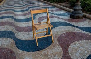 uitleg promenade in Alicante Spanje mijlpaal met houten leeg stoel Aan mozaïek- foto