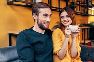 knap Mens in trui en vrouw met een kop van koffie datum liefde restaurant cafe foto