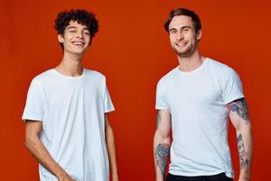 twee mannen in wit t-shirts Aan een rood achtergrond vriendschap foto