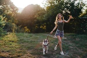 een vrouw loopt met een hond in de Woud gedurende een avond wandelen in de Woud Bij zonsondergang in herfst. levensstijl sport- opleiding met uw geliefde hond foto