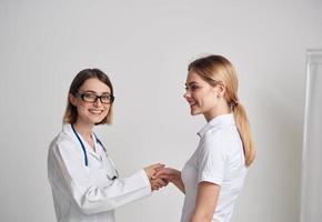 een vrouw in een t-shirt kwam naar zien een dokter in een medisch japon foto