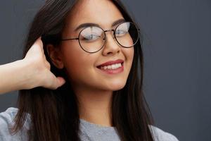 mooi vrouw bril Aan gezicht mode levensstijl grijs t-shirt grijs achtergrond foto