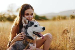 vrouw en haar schor hond gelukkig wandeling door de gras in de park glimlach met tanden vallen zonsondergang wandelen met huisdier, reizen met een hond vriend foto