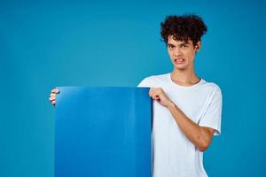 vent in een wit t-shirt Holding een poster mockup reclame blauw achtergrond foto