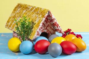kleurrijk eieren symboliseert Pasen, met een speelgoed- huis, bloemen Leuk vinden een tuin foto
