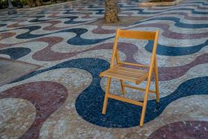 uitleg promenade in Alicante Spanje mijlpaal met houten leeg stoel Aan mozaïek- foto