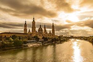 landschap van de Spaans stad van saragossa met de basiliek en de ebro rivier- in de achtergrond van de zon instelling in de lucht foto