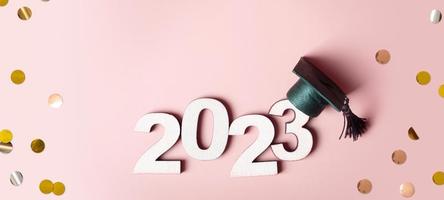 klasse van 2023 concept. houten aantal 2023 met afgestudeerd pet Aan gekleurde achtergrond foto