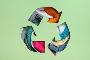tweede hand, circulaire mode en recycling concept. kleurrijk kleren onder papier besnoeiing recycling symbool foto