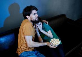 mannen en Dames Aan de bankstel in een donker kamer aan het kijken een verschrikking film foto