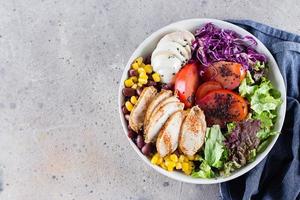 gezond lunch salade met kip, ei, tomaten, sla, rood bonen, rood kool, saus, top visie foto