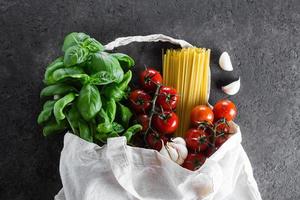 gezond Product voor Italiaans pasta in kleding stof zak Aan donker tafel. herbruikbaar zak met boodschappen. foto