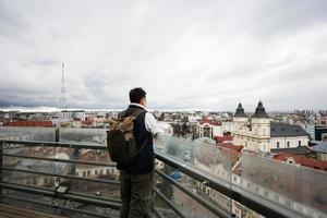 terug visie van Mens toerist met rugzak staan Aan achtergrond van panorama visie stad. foto