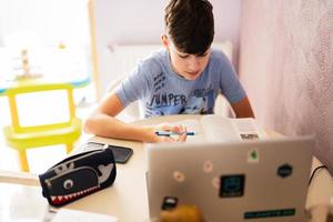 jong tiener- jongen hebben video conferentie telefoontje met leerling gebruik makend van webcammen. online onderwijs en e-learning concept. huis quarantaine afstand aan het leren. foto