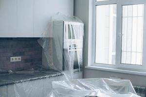 meubilair gedekt met plastic Aan de keuken. reparaties in appartement. onvoltooid appartement interieur foto