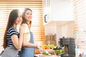 lesbienne paar staand in keuken. lesbienne paar staand in een modern keuken achter een teller Koken voedsel samen. in liefde lgbt vrijheid concept. liefhebbend en zorgzaam paar Koken. selectief focus. foto