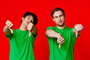 vrolijk vrienden in groen t-shirts gebaren met handen geïsoleerd achtergrond foto