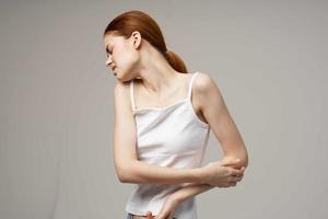 vrouw in wit t-shirt elleboog pijn artritis chronisch ziekte licht achtergrond foto