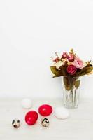 Pasen vakantie geschilderd eieren en een boeket van bloemen in een vaas Aan de tafel foto