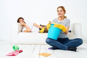 de man leugens Aan de bankstel terwijl zijn vrouw reinigt omhoog de interieur werk foto