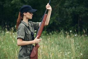 vrouw zwart pet en een groen jumpsuit is Holding een wapen in zijn handen foto