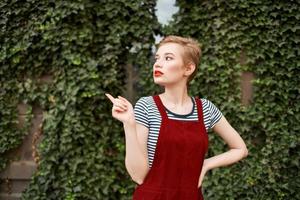 mooi vrouw met kort haar- Aan de straat tegen de achtergrond van struiken foto