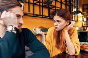 gelukkig vrouw in een trui gebaren met haar handen pret emoties en een Mens in een trui zit in een cafe foto