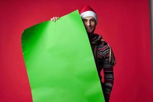 emotioneel Mens in een Kerstmis hoed met groen mockup rood achtergrond foto