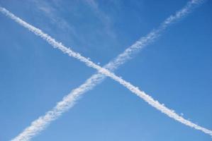 contrails in blauw lucht. wit kruis gemaakt van stoom- sporen van vliegtuigen foto