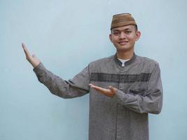 Moslim Aziatisch Mens glimlachen en hand- richten naar de Rechtsaf kant foto