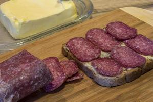 boter, een plak van brood met boter, gesneden salami Aan een snijdend bord. foto