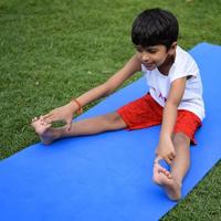 Aziatisch slim kind aan het doen yoga houding in de maatschappij park buitenshuis, kinderen yoga houding. de weinig jongen aan het doen yoga oefening. foto