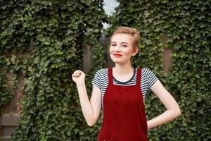 mooi vrouw met kort haar- Aan de straat tegen de achtergrond van struiken foto