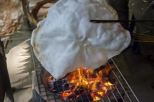 hoe naar koken vlieger crackers of khao kriap Wauw door grillen deeg lakens Aan houtskool fornuis, een oude Thais nagerecht. foto