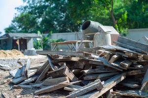 close-up stapel nutteloos hout op de bouwplaats met wazig betonmixer op achtergrond foto