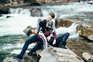 jongen en meisje in warme truien wandelen langs een bergrivier, liefdesverhaal foto