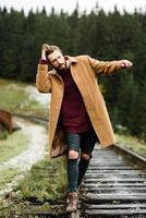 brute bebaarde man loopt op de sporen in de Karpaten, op de achtergrond hoge sparren foto